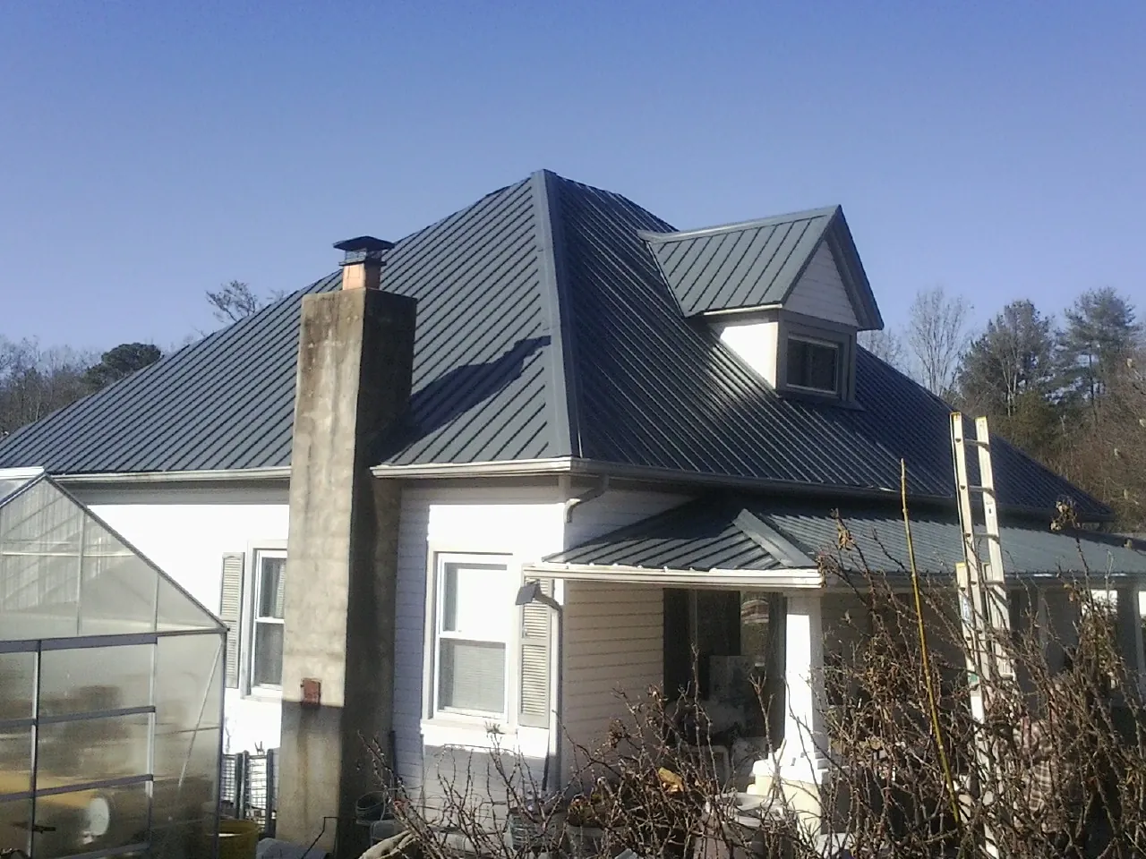 Dark blue standing seam metal roof on a white farmhouse with dormer — Slate & Tile Roof Repair by Roofing Brothers in Barrington