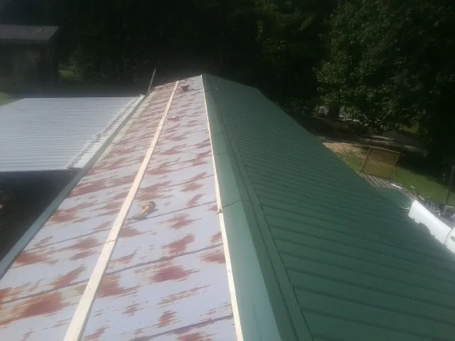Old rusted panels beside newly installed green metal roofing — Wind Damage Roof Repair by Roofing Brothers in Barrington